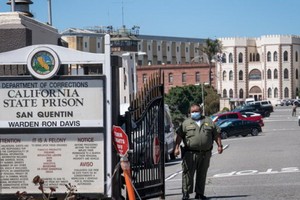 一名加州懲戒及改造局（CDCR）的官員戴著口罩站在聖昆廷州立監獄的前門。（圖源：Getty Images）