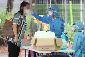 韓國首爾江西衛生站的篩查診所一名市民接受體溫檢測。（圖源：韓聯社）