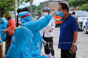 防疫工作人員給峴港市五行郡市民測量體溫。（圖源：越通社）