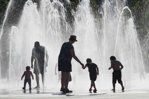 在法國東部城市科爾馬，一家大小在地面噴泉上淋水消熱。（圖源：AFP）