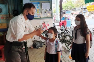 禮文華文中心老師在校門前給學生測量體溫。