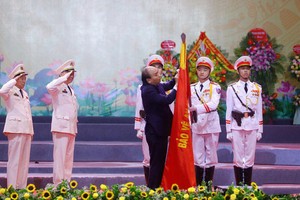 政府總理阮春福代表黨及國家領導為越南人民公安傳統旗幟上佩掛一等軍功勳章。（圖源：杜忠）