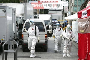 公共衛生職員在首爾一個「愛第一」教會址附近進行消毒。（圖源：AP）