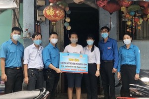 貧困青年阮玉水仙（中）從溫陵會館理事林曉東手中接過善款。