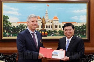 市人委會主席阮成鋒（右）向英國駐本市總領事伊恩‧比本斯贈送紀念品。（圖源：市黨部新聞網）