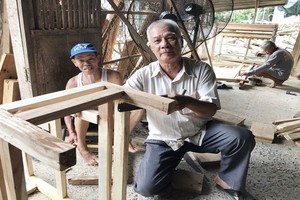 裴文盧（中）與慈善木匠組成員們在釘造凳子。