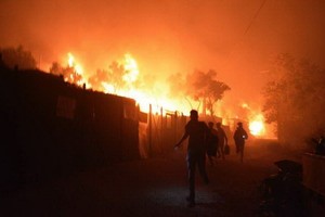 當地時間9月9日，希臘萊斯博斯島的莫里亞難民營發生大火後，難民離開著火地。（圖源：AP）