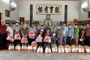義安會館理事長陳裕(左一)向鄉親派發賑濟品。