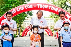 政府常務副總理張和平（中）和各位領導向小朋友們贈送安全帽。（圖源：元姮）