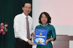 梅氏紅花同志（右）從市人委會常務副主席黎清廉手中接過人事委任《決定》。（圖源：市黨部新聞網）