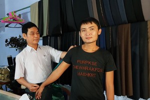 范勇（左）為顧客量身定制衣服。