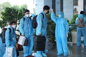 外國專家們進入自費隔離酒店前測量體溫。