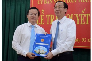 新任平盛郡人委會主席丁克輝（左）從市人委會常務副主席黎清廉手中接過人事委任《決定》。（圖源：蔡芳）