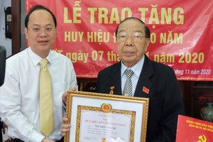 市委副書記、市委組織處主任阮胡海向阮文志同志（右）頒授60年黨齡紀念章。（圖源：梅花）