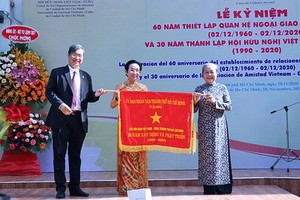 市各友好組織聯合會王德煌軍（左）向市越南-古巴友好協會代表贈送市人委會傳統錦旗。（圖源：明協）