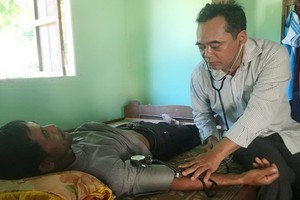 慶永縣縣委書記牟文飛為連創鄉貧民診病。