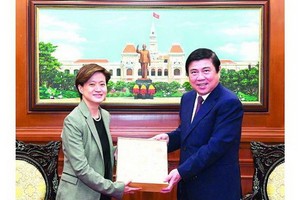 市人委會主席阮成鋒（右）向新加坡駐越南特命全權大使凱瑟琳‧王贈送紀念品。（圖源：越勇）