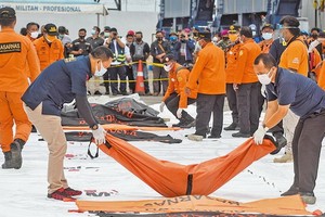 1月10日，印尼當局已撈到部分遇難者遺骸，放到岸上等候進一步相驗。（圖源：新華社）