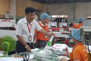 南泰山公司黨支部書記阮梅雄（左）與同事們討論產品質量。