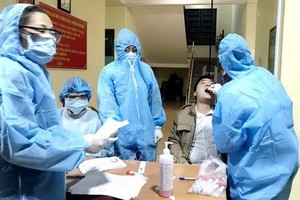 防疫工作人員向新冠肺炎疑似患者進行深喉拭子取樣測試。（圖源：越通社）