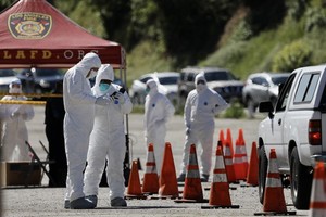 工作人員在美國洛杉磯新型冠狀病毒免下車檢測站工作。（圖源：新華社）