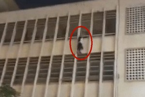 一名女生雙手攀住學校四樓護欄墜樓，懸掛在空中。（圖源：視頻截圖）