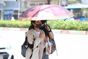 一對情侶撑著伞走在烈光下。（圖源：越通社）