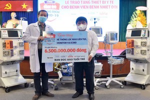 《年輕人報》總編輯黎世渚（右）象徵性向市熱帶病醫院院長阮文永洲醫生（左）移交總值65億元的防疫醫療設備。（圖源：緣潘）