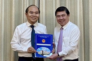 陳文七同志（左）從市人委會主席阮成鋒手中接過人事委任《決定》。（圖源：潘阮）