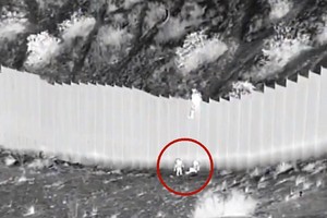 兩名女童被扔過邊境牆（視頻截圖）。