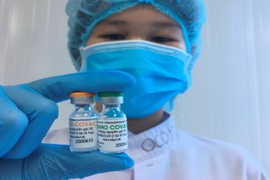 一名醫務人員拿著兩小瓶國產新冠疫苗。（圖源：冰心）