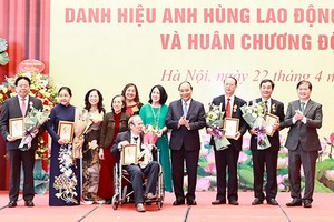 國家主席阮春福（右四）與榮獲革新時期勞動英雄稱號的代表及家屬合照。（圖源：越通社）