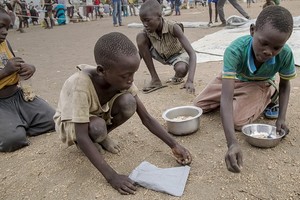 在烏干達的一個難民營帳區，南蘇丹孩子把派發糧食時掉在地上的榖物逐粒拾起來。（圖源：互聯網）