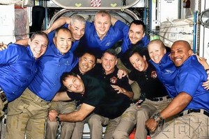 新到站的 4 名宇航員（黑衣者）同空間站內的宇航員們一起合影。（圖源：共同社）