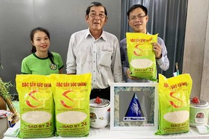 ST25大米品牌研發人胡光郭（中）與推銷員在推介ST25大米品牌。（圖源：H.Đ）