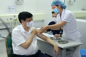 醫護人員為衛生部長阮清隆（左）注射新冠疫苗。（圖源：越通社）