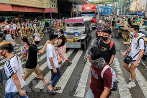 菲律賓馬尼拉街頭的民眾佩戴防護用具出行。（圖源：新華社）