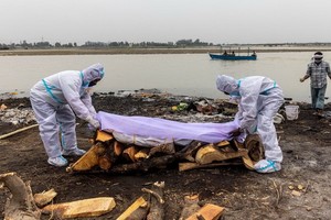 死者親屬在恆河邊準備火化遺體。（圖源：路透社）