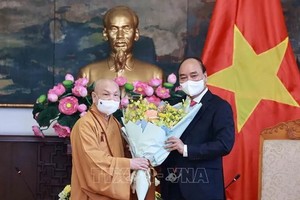 國家主席阮春福（右）接見越南佛教教會理事會理事長釋善仁和尚時贈送鮮花祝賀。（圖源：越通社）
