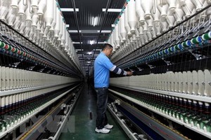 一名工人在一家紗線車間操控生產線。（圖源：越通社）