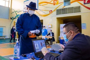 這是6月9日，蒙古人民黨總統候選人呼日勒蘇赫（中）在蒙古國首都烏蘭巴託一處投票站準備投票。（圖源：新華社）