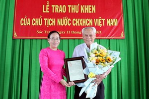 受國家主席的委託，滀臻省人委會副主席黃氏艷玉（左）向陳剛老人家轉交表彰函。