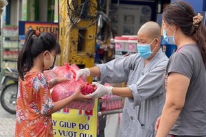 妙法寺住持釋宏心法師向貧困者贈送救濟品。