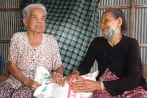 五婆（右）帶著善良的笑容向泰婆贈送大米。