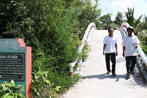 名雄（右）站在他設計和搭建的農村橋。