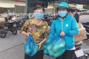 華人商販應氏蓮(左)將募集到的蔬菜送給隔離區居民。