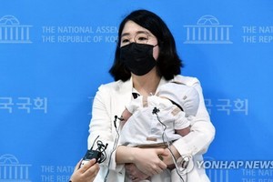 7月5日，在位於首爾市汝矣島的國會辦公大樓，基本收入黨籍國會議員龍慧仁抱著孩子答記者問。（圖源：韓聯社）