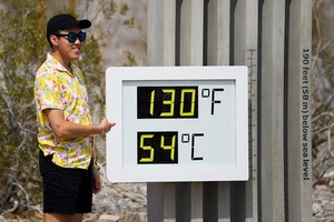 遊客與門口的溫度顯示器合影。（圖源：Getty Images）
