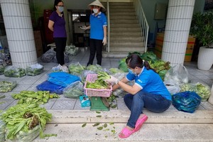 防疫隊伍的婦女正在包裝蔬菜送到隔離區。
