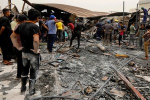 7月13日，人們聚集在伊拉克南部濟加爾省發生火災的新冠定點醫院。（圖源：路透社）